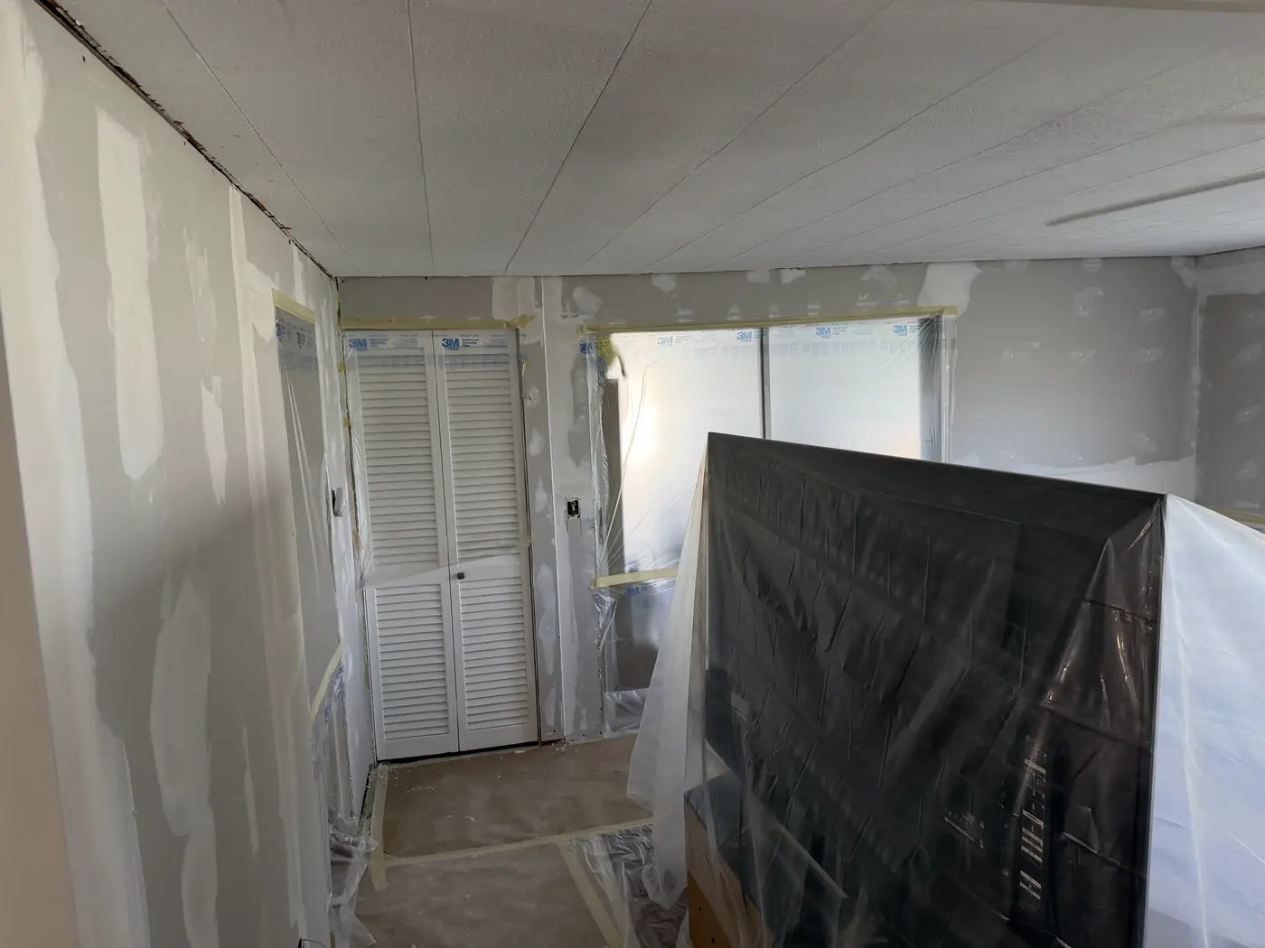 Room masked for drywall work with taped windows and protective coverings over furnishings, Handyman Pros Florida